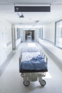An empty hospital coridoor has an empty bed in it. 
